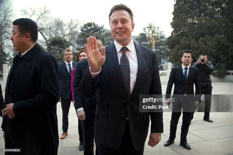 Tesla CEO Elon Musk, center, waves as he waits for a meeting with ...