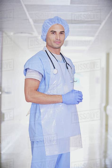 Portrait of male doctor wearing scrubs in hospital corridor - Stock Photo - Dissolve