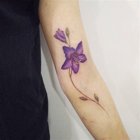 Purple lily tattoo on the left arm.