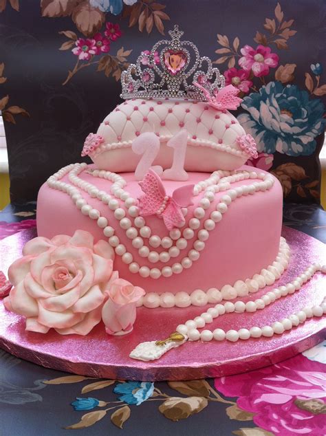 a pink cake with pearls and a tiara on top