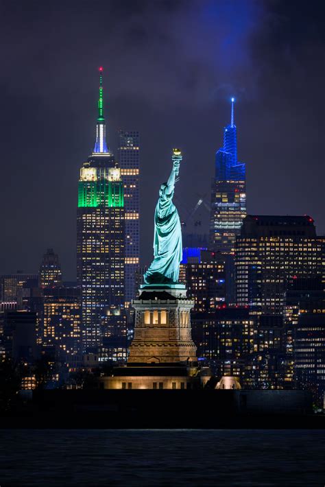 Night view of the Statue of Liberty with the Empire State Building lit ...