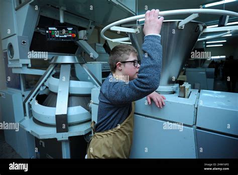 Boy with Down syndrome dressed in work clothes standing near bread makeup machine at the Dutch ...