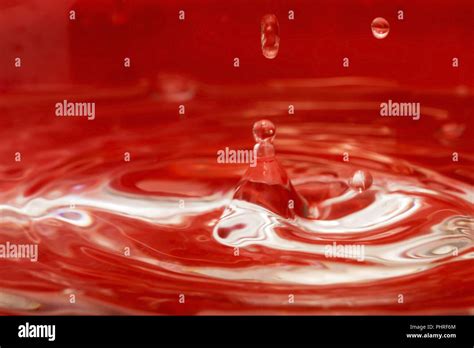 Water drop on a red background Stock Photo - Alamy