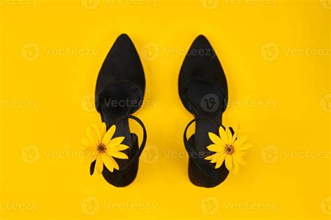 Suede black court shoes with yellow Topinambur flower bud on strap, yellow background, trendy ...