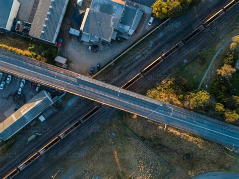 Image of Empty coal train passing under bridge over railway seen from top down aerial view ...