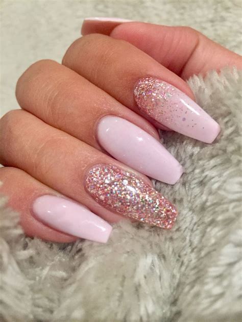 squoval nails in baby pink, decorated with pink glitter, and attached to a hand, gripping a ...