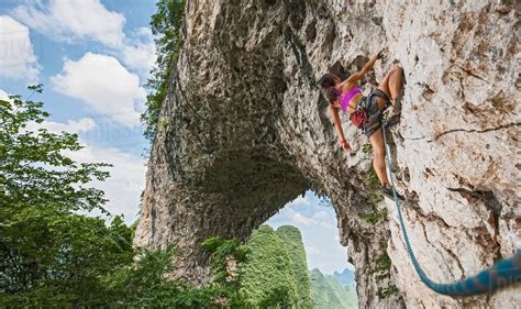 Female climber climbing on Moon Hill limestone arch in Yangshuo, Guangxi Zhuang, China - Stock ...