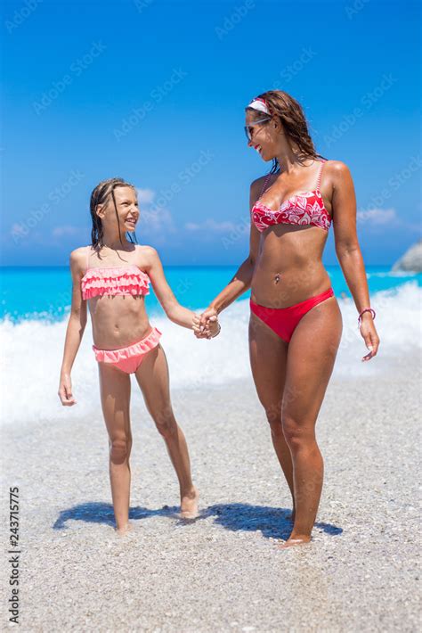 Happy young mother walking on the beach with her daughter 素材庫相片 | Adobe Stock