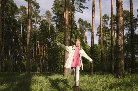 Girl walking on log in forest stock photo