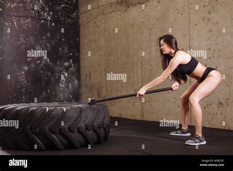 woman smashing large tire with sledgehammer during intense workout in fit gym Stock Photo - Alamy