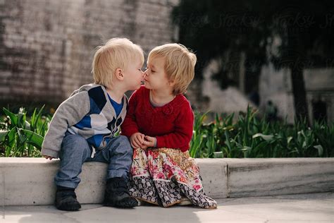 "Two Small Children Sitting On A Low Wall Share A Kiss." by Stocksy Contributor "Julia Forsman ...