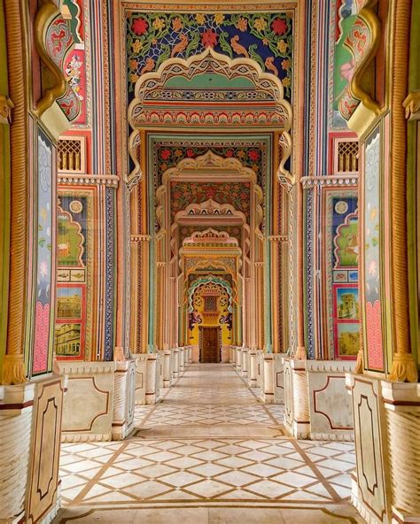 an ornate hallway with colorful painted walls and columns on either side, leading to a doorway