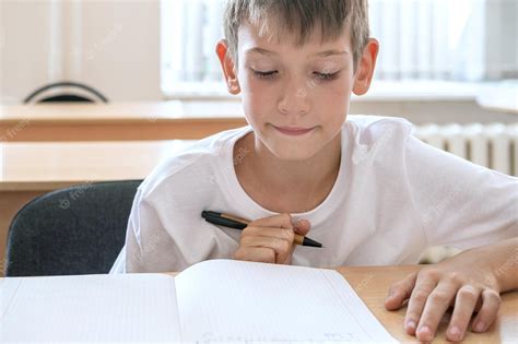 Premium Photo | A focused boy doing homework writing text in a notebook ...