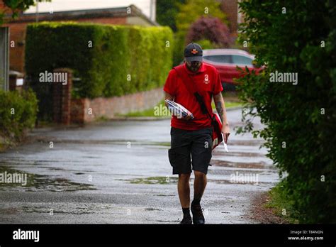 Ashford, Kent, UK. 11 May, 2019. UK Weather: A local postman gets caught in a sudden downpour in ...