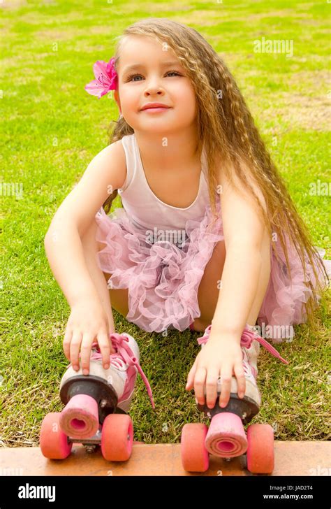 Little girl preschool beginner sitting in the grass with her roller ...