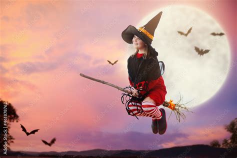 Halloween witch flying broom. Huge moon and bat. Stock Photo | Adobe Stock