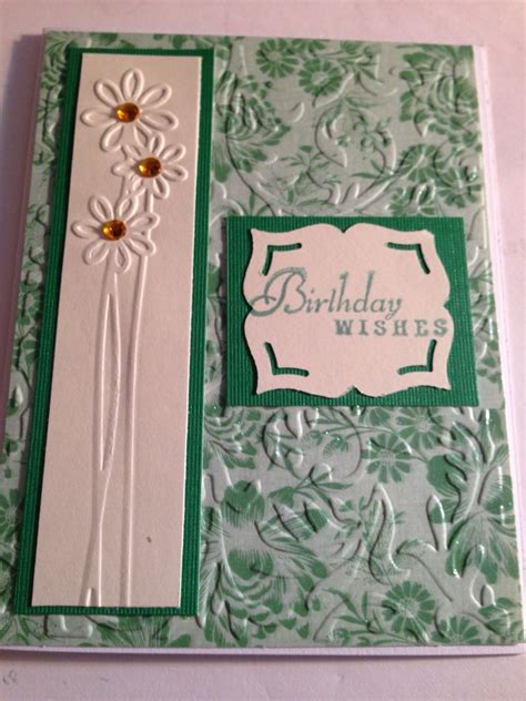 a green and white birthday card with daisies on the front, and an ...