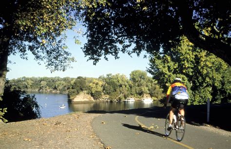 a bicyclist rides down a paved path near the water