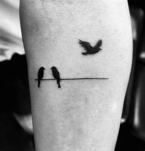 two birds sitting on a wire and one is flying away from the other tattoo design