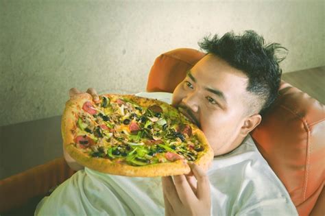 Premium Photo | Fat man eating a big pizza with gluttony expression