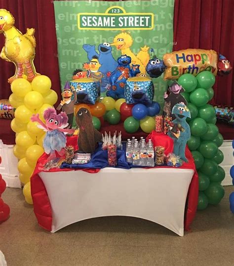 the sesame street birthday party table is set up with balloons, streamers and decorations