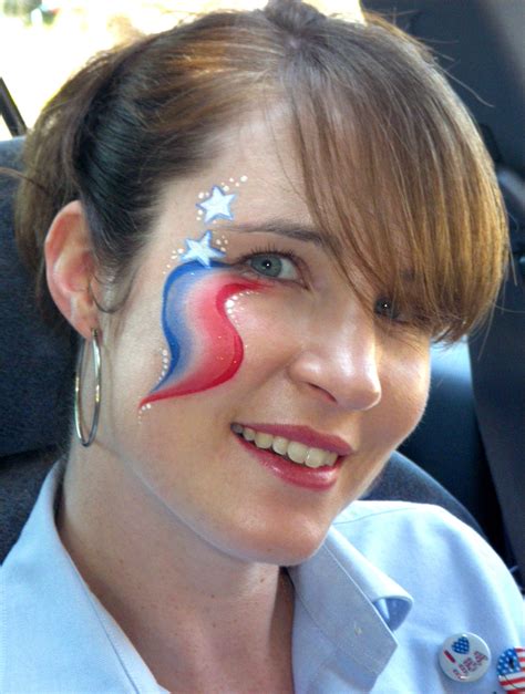 a woman with her face painted in the colors of the american flag