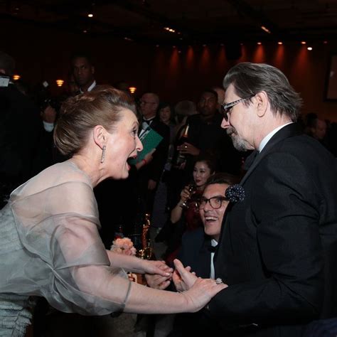 a man in a tuxedo shakes hands with a woman in a sheer dress