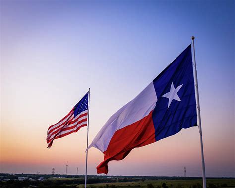 Texas and American flags waving above the Texas Countrside Photograph by John Davis