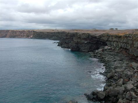 a rocky cliff overlooks the ocean on a cloudy day