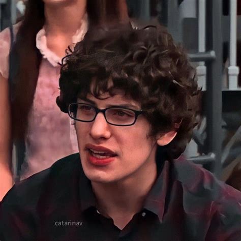 a close up of a person wearing glasses and a black shirt with long curly hair