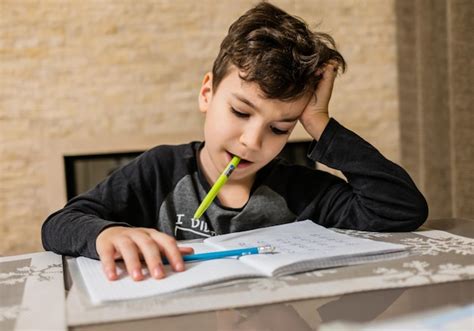 Premium Photo | Cheerful and funny schoolboy solves homework emotionally thinks about how to ...