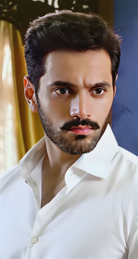 a man with a goatee and beard wearing a white shirt looking at the camera