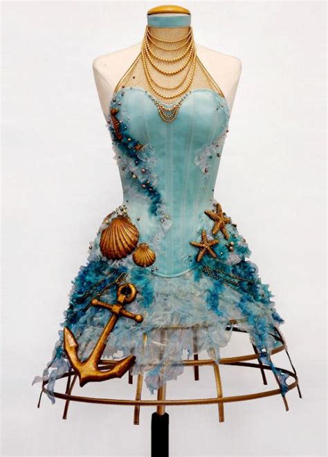 a mannequin dressed in blue and gold with an anchor, sea shell, pearls and chains