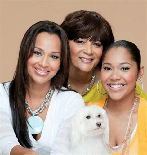 three women and a dog posing for a photo with one woman holding a small white dog