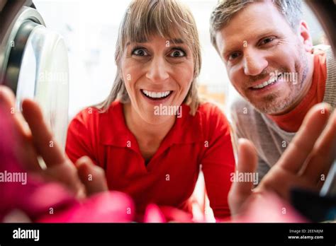 Couple looks cheerfully in a washing machine Stock Photo - Alamy