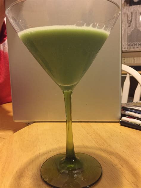 a green drink sitting in a glass on top of a table