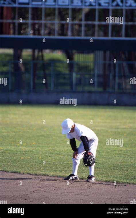 Japanese little league baseball player stands in the outfield waiting ...