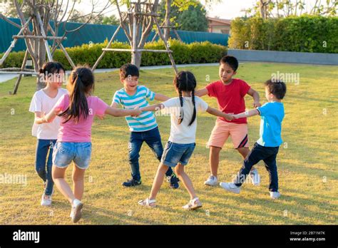 Large group of happy Asian smiling kindergarten kids friends holding hands playing and dancing ...