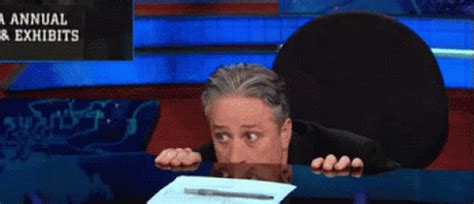 Peek GIF - JonStewart HidingBehindDesk Hide - Discover & Share GIFs