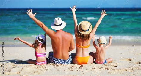 happy family father, mother and children backs on beach at sea. Stock Photo | Adobe Stock