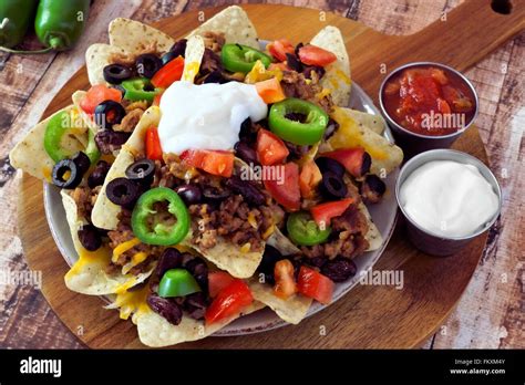 Mexican nacho chips topped with ground meat, jalapenos, tomatoes, beans and melted cheese with ...