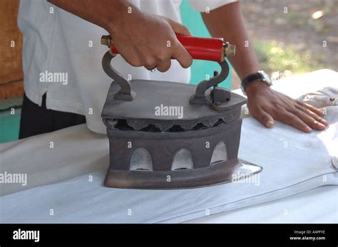 ANG77687 Man ironing pressing clothes with traditional coal iron Stock Photo: 6343165 - Alamy