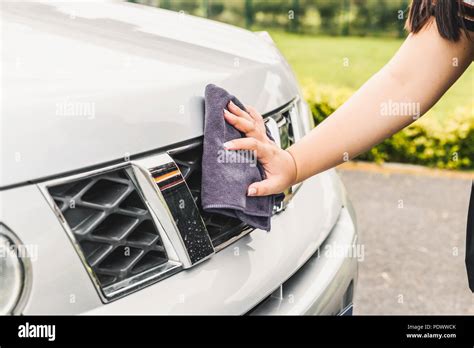 Closeup picture, image young woman, driver, dry wiping her car with microfiber cloth after ...