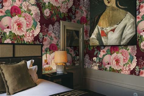 a bedroom with floral wallpaper and paintings on the walls