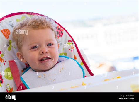 Gorgeous happy toddler eating food in high chair Stock Photo - Alamy