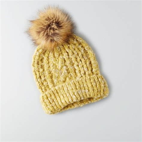 a yellow knitted hat with a brown pom - pom on the top