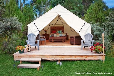 a tent set up in the middle of a yard with lawn furniture and flowers on it