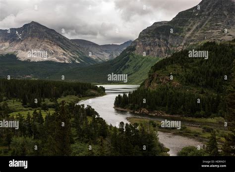 Tranquil river flowing through rugged mountains in Glacier National Park; Browning, Montana ...