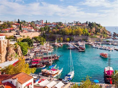 boats are docked in the water near an old city wall and some buildings with red roofs