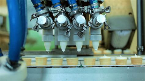 Food processing equipment. Waffle cones filling with ice cream. Automated production line. Food ...